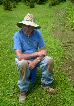 still gardening in 2004 with small Christmas trees growing in background and wearing a goofy hat my mom bought for him at a garage sale to protect him from the sun